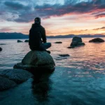 Un hombre en soledad viendo una puesta de sol en la costa