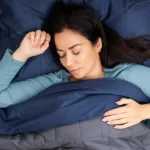 Une femme dormant dans un lit bleu et gris.