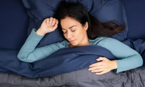 Une femme dormant dans un lit bleu et gris.