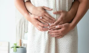 Image de quatre mains posées sur le ventre d'une femme pendant la période périnatale.